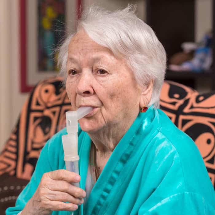 Elderly woman doing incentive spirometry during pulmonary rehab to help with hard time breathing.